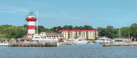 A lighthouse, a marina with boats, and a building with a red roof.