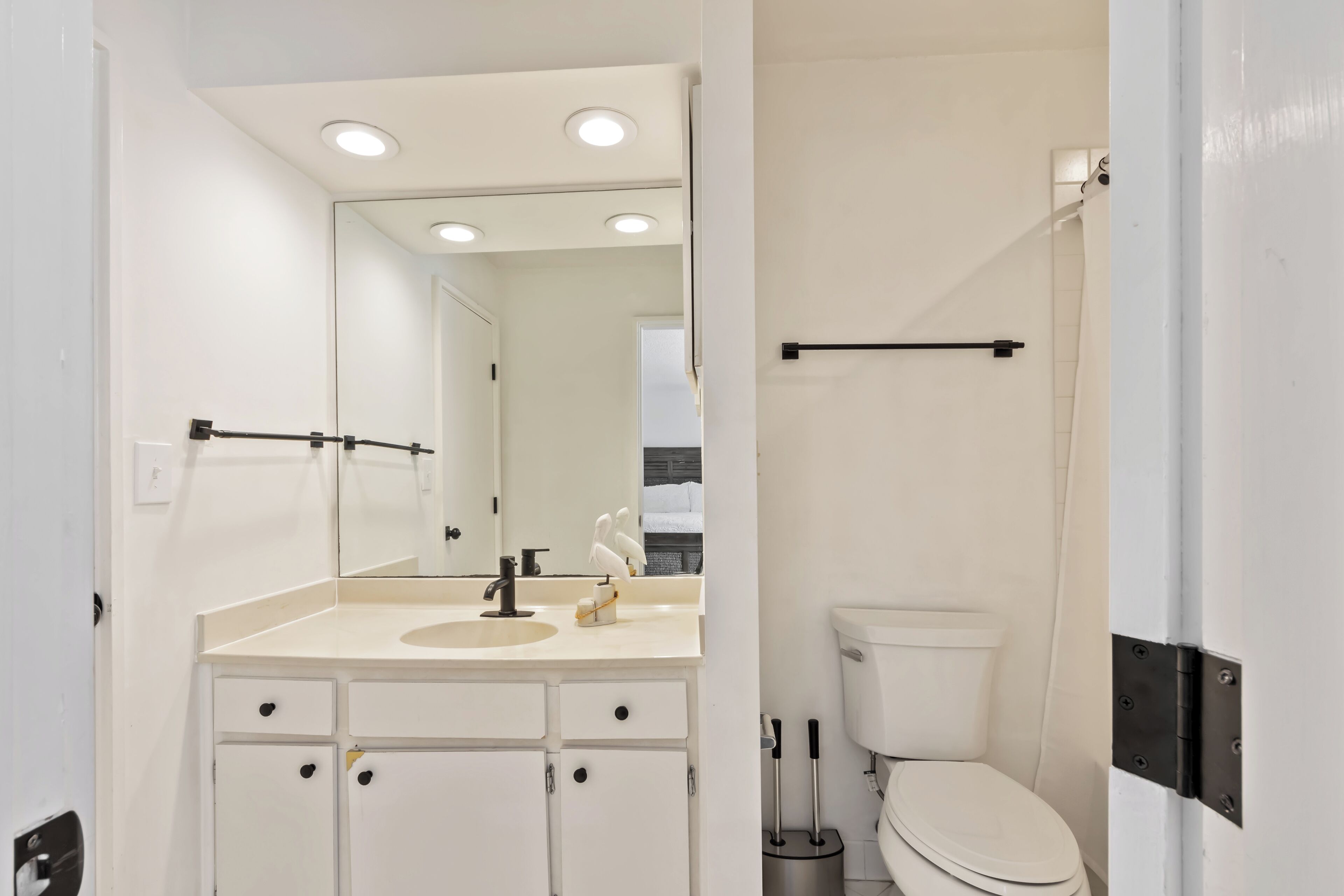 Ein modernes Badezimmer mit Waschbecken, Spiegel und Toilette in Weiß.