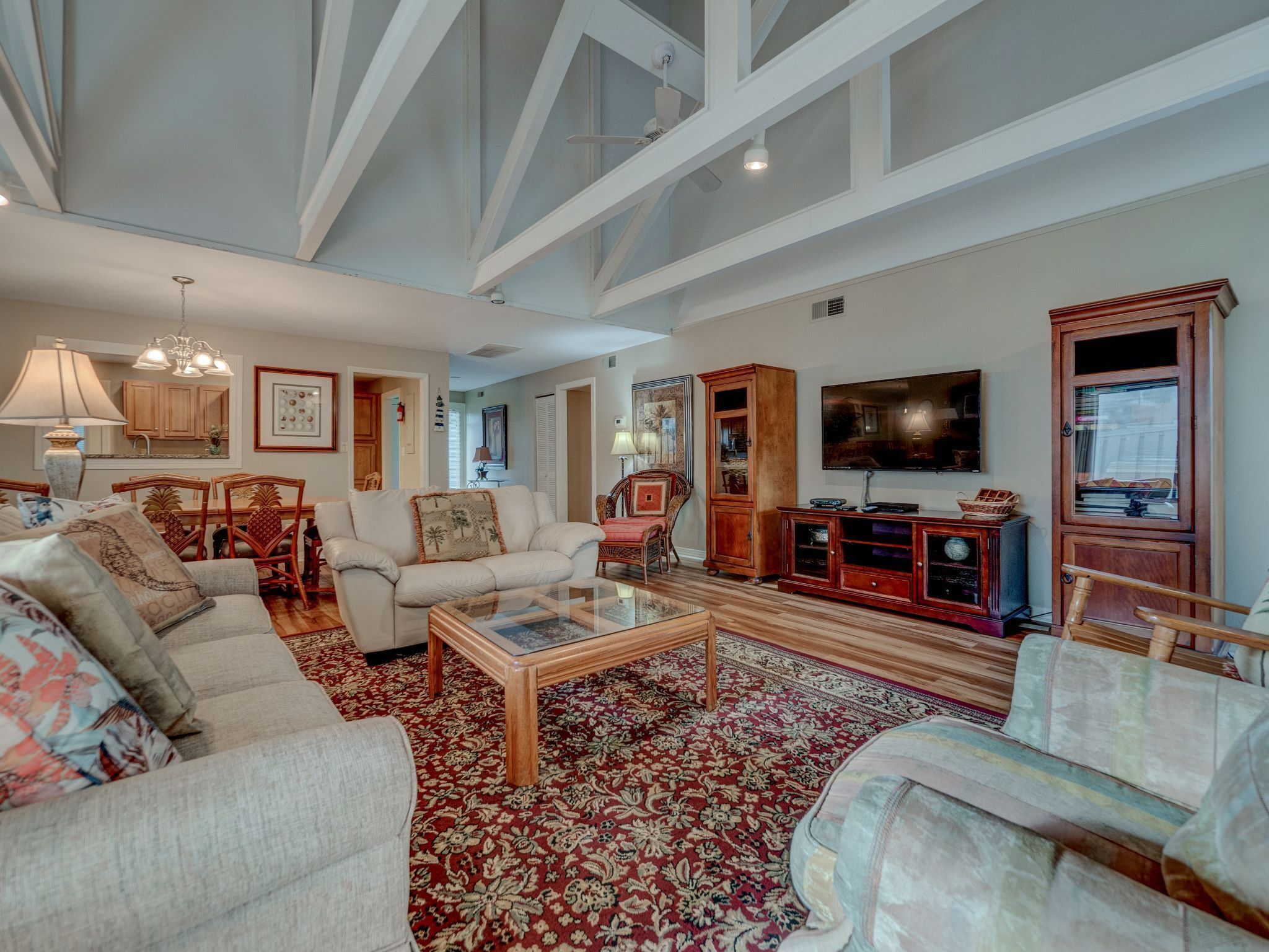A spacious living room with a high ceiling, a large TV, and a wooden cabinet.