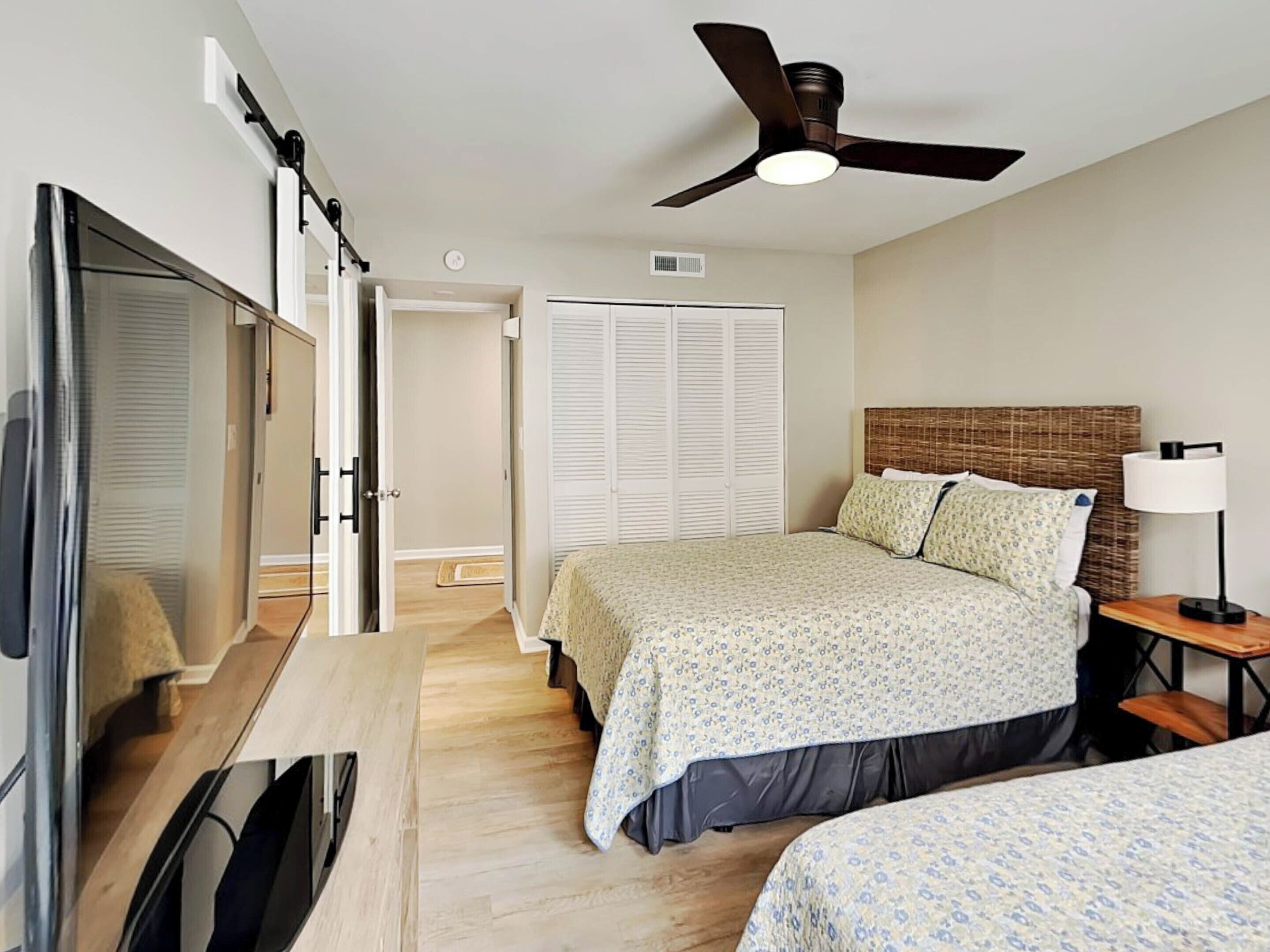 Un dormitorio con cama, mesita de noche, lámpara y ventilador de techo.