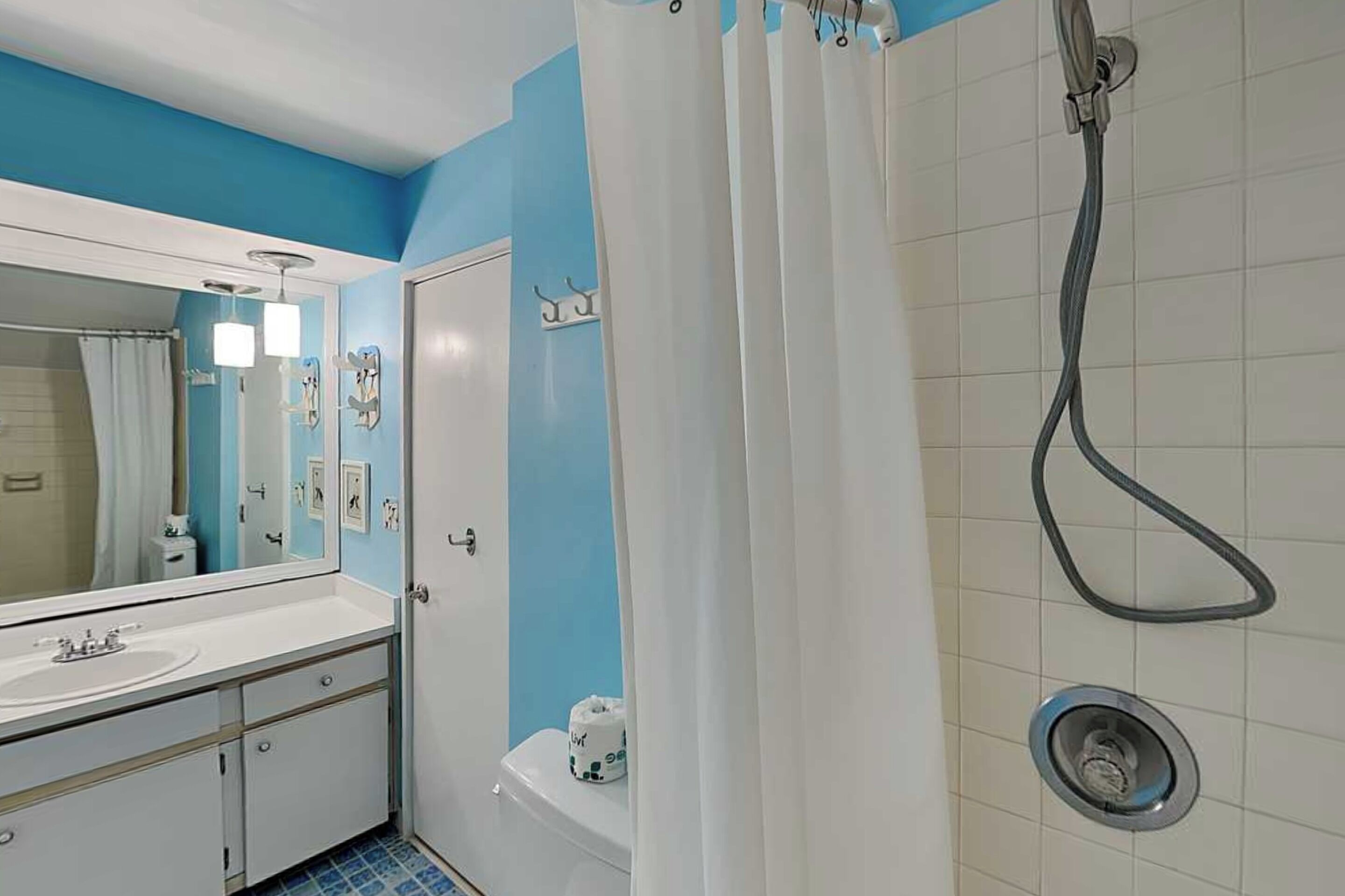A bathroom with a white sink, mirror, and shower.