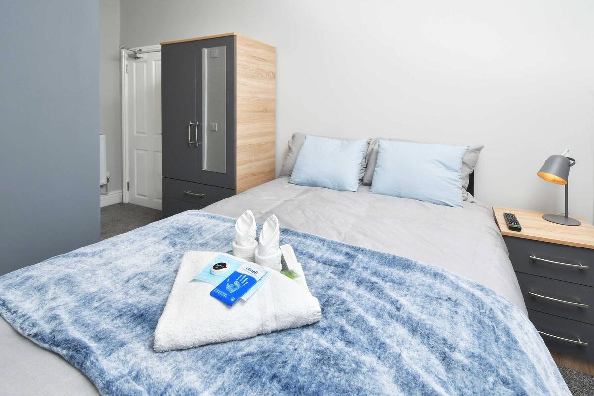 Una habitación de hotel con cama, armario, mesita de noche y lámpara.
