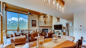 A spacious living room with a large wooden dining table, leather sofas, and a stone fireplace. - Potato Patch (Vail)