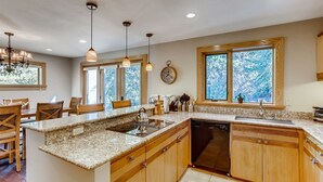 A kitchen with wooden cabinets, granite countertops, a built-in dishwasher, and pendant lighting. - Potato Patch (Vail)