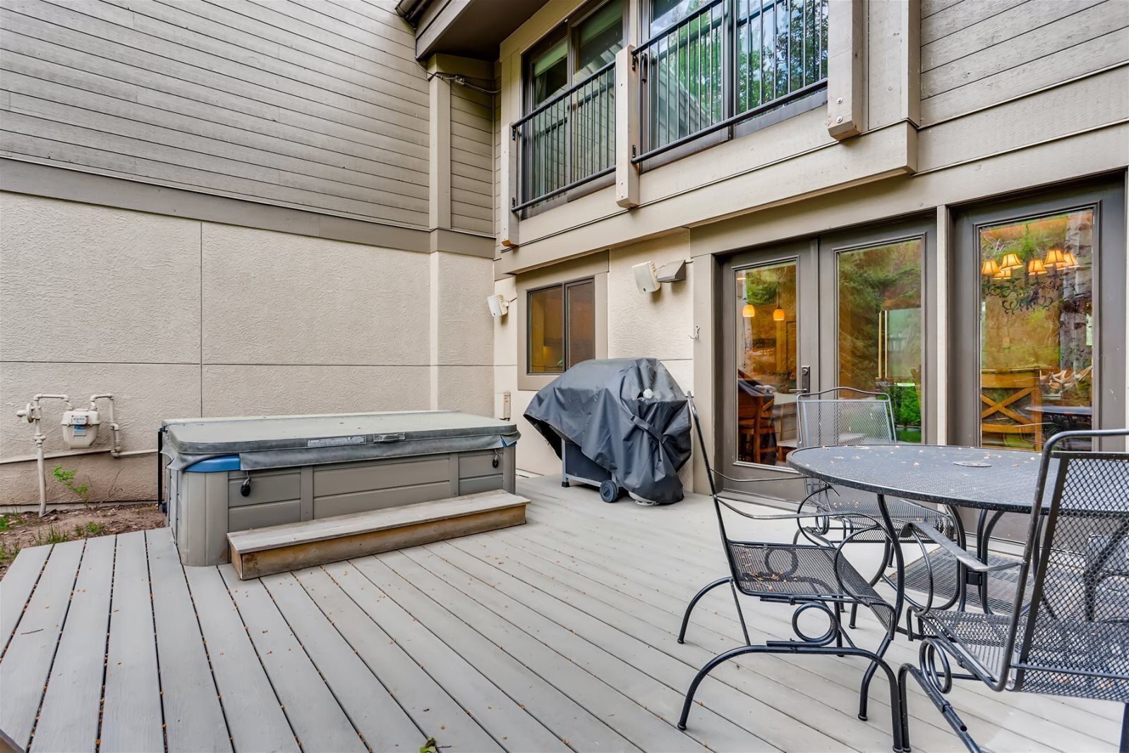 A patio with a hot tub, covered grill, and outdoor seating area.