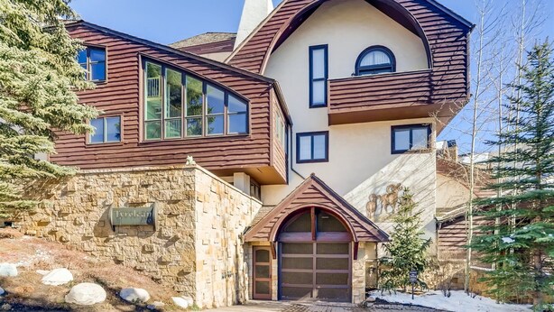A multi-story house with a stone facade, large windows, and a garage. - Tyrolean 6 (Vail)