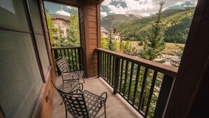 A balcony with two metal chairs and a view of a mountainous landscape. - Springs 8876 (Keystone)
