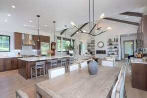 A modern kitchen with a large island, pendant lighting, and a view of the living area.