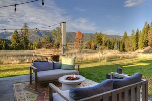 An outdoor seating area with a fire pit, a wicker chair, and a sofa.