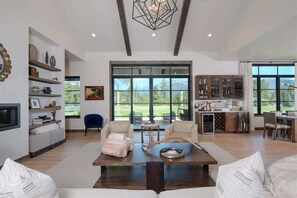 A spacious living area with a large window, a dining area, and a kitchen.