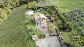 An aerial view of a stone house with a tiled roof, surrounded by a well-maintained garden and a swimming pool. - Villa Elisa, villa with private pool & air Co near Reschio Castle (Città di Castello)