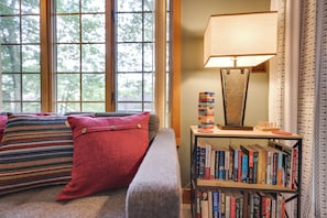 A cozy living room with a sofa, pillows, a bookshelf, and a lamp.