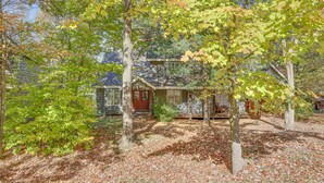 A house surrounded by trees with a red door and a small porch. - Ridge Run Retreat (White Haven)