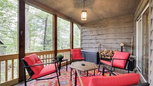 A wooden deck with red chairs and a table, surrounded by large windows offering a view of trees. - Ridge Run Retreat (White Haven)
