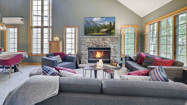A cozy living room with a stone fireplace, large windows, and comfortable seating. - Ridge Run Retreat (White Haven)