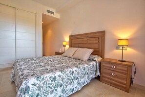 A bedroom with a bed, two bedside tables, a wooden nightstand, and a wardrobe.