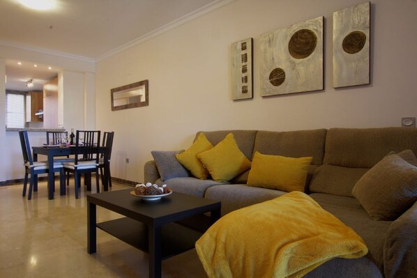 A living room with a sofa, a coffee table, and a dining area with chairs and a table.