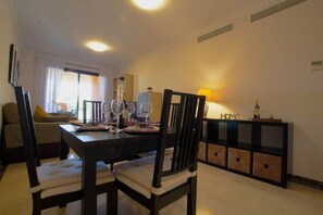 A dining area with a table set for four, a sofa, and a cabinet with a lamp.