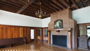 A spacious room with a wooden floor, a fireplace, and a chandelier. - Golf & Hunting Retreat - Luxury Historic Barn Near Pinehurst (Southern Pines)