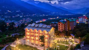 Un hotel de varios pisos, con un espacio exterior bien iluminado y vistas a las montañas circundantes.