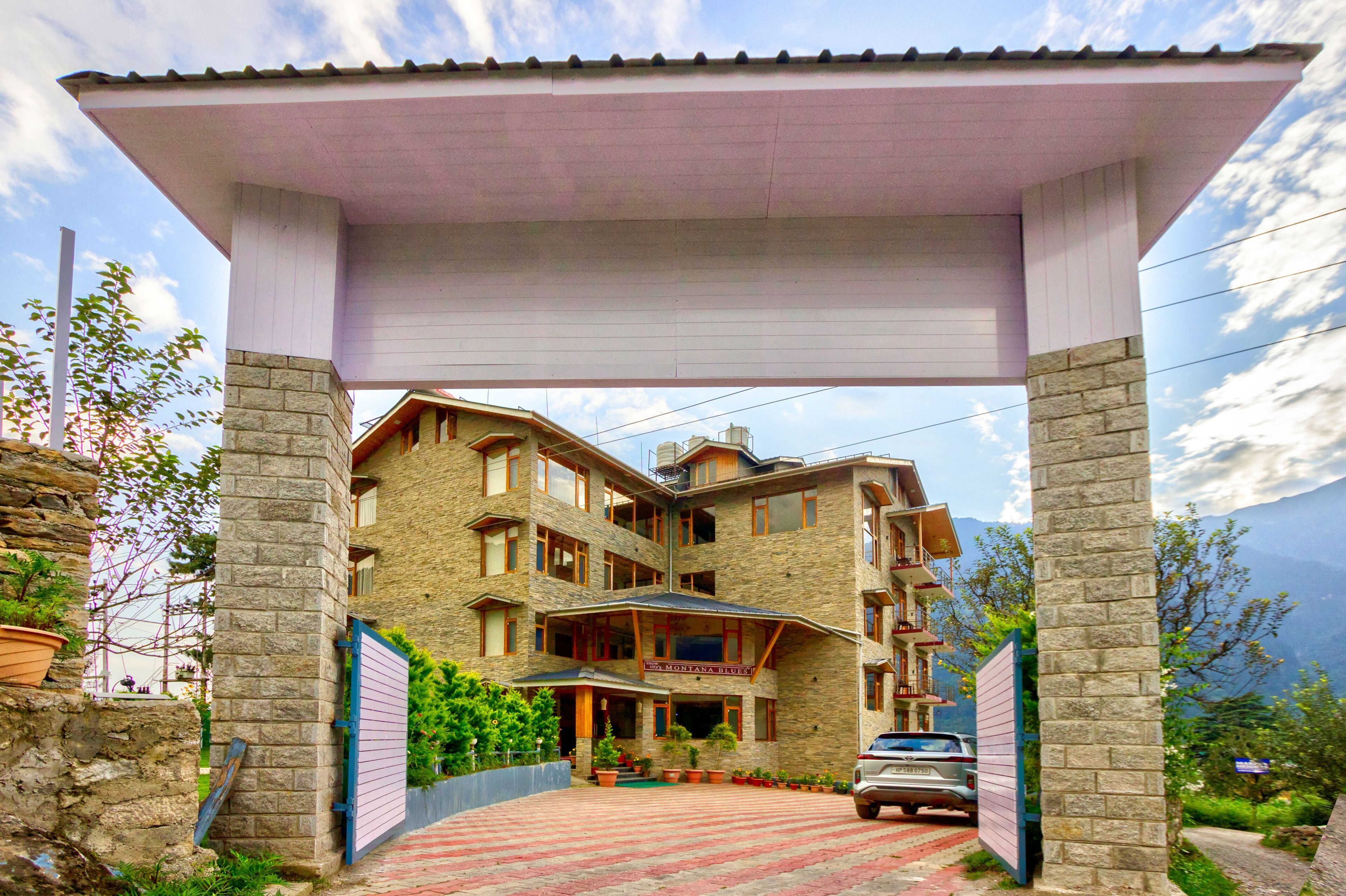 A multi-story building with a stone facade, a covered entrance, and a car parked in front.