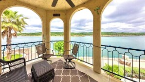 Un área de estar al aire libre con techo y vistas a un lago y palmeras.