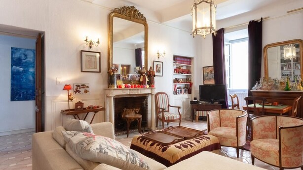 Un salon comprenant un canapé, des fauteuils, une cheminée, un téléviseur et une bibliothèque.