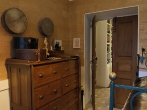 A wooden dresser with multiple drawers, a blue metal railing, and a door leading to a room with a tiled floor.