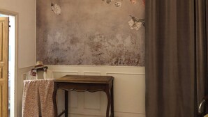 Une pièce avec un papier peint à motifs floraux, une petite table en bois et une porte.