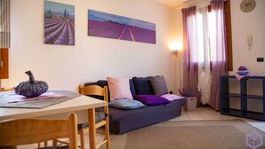 Una sala de estar con sofá, mesa de comedor y dos cuadros en la pared.