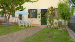 Un patio con un camino empedrado, una mesa pequeña con sillas y una puerta verde.