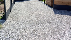 A gravel pathway leading to a fenced area with wooden planters and a building with a sloped roof. - Suite-Designer-Whirlpool bath (Saint-Blimont)