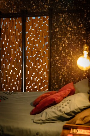 Un dormitorio con cama, almohadas y una pared con diseño geométrico.