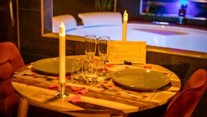 A dining table set with plates, glasses, a candle, and a menu. - Suite-Designer-Whirlpool bath (Saint-Blimont)