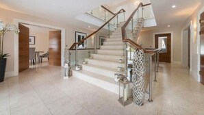 A spacious interior with a modern staircase, a dining area, and a hallway leading to another room.