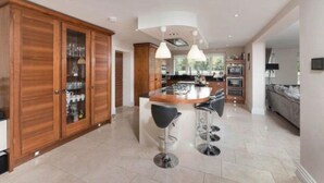 A spacious kitchen with a central island, wooden cabinets, and modern pendant lighting.