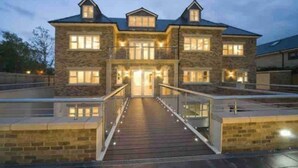 A large, multi-story stone building with a central entrance and a covered walkway leading to the main doors.