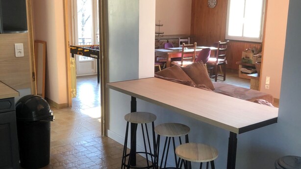 Una cocina con barra, taburetes y vistas al comedor.