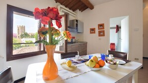 A dining area with a table set for two, a vase with flowers, and a view of a tower through a window. - 2 Bed-sleeps 6-aircon-town Centre-free Parking (Montagnana)