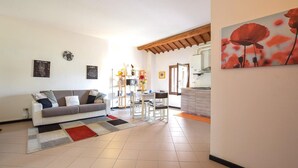 A living room with a sofa, a dining table with chairs, a kitchen area, and a painting on the wall. - 2 Bed-sleeps 6-aircon-town Centre-free Parking (Montagnana)