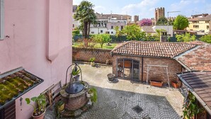 A courtyard with a traditional brick building, a water well, and surrounding greenery. - 2 Bed-sleeps 6-aircon-town Centre-free Parking (Montagnana)