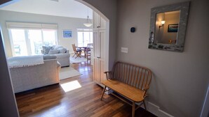 Een woonkamer met een bank, een houten zitbank en een eethoek met stoelen en een tafel.