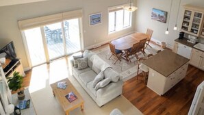 Een ruime loft met hoge plafonds, een eethoek, een zithoek met een bank en salontafel, en een keuken.