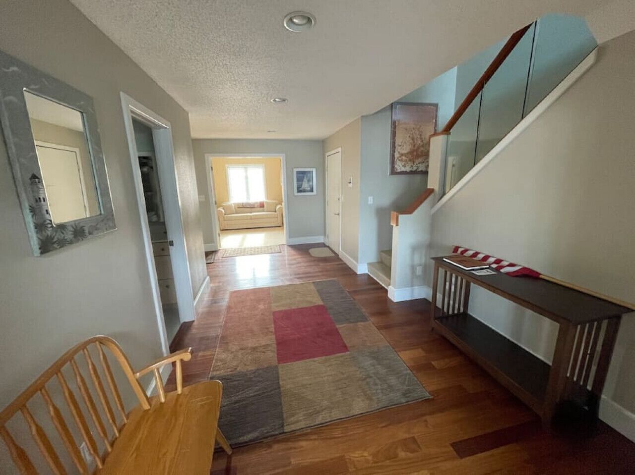 Un couloir avec un banc en bois, un tapis à carreaux et un escalier doté d’une rampe en bois.