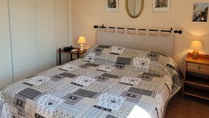 Ett sovrum med en säng, två sängbord, en väggmonterad luftkonditioneringsanläggning och inramade tavlor.
