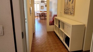 En hall med en matplats i bakgrunden, ett vitt konsolbord och en stor, abstrakt målning på väggen.
