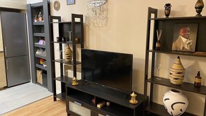 Un salon moderne doté d’un téléviseur à écran plat, d’un meuble de rangement en bois foncé et d’objets décoratifs.