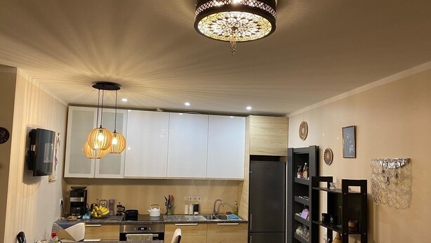 Une cuisine moderne avec des meubles blancs, un réfrigérateur noir et un coin repas comprenant une table et des chaises.