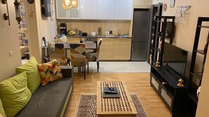 Une cuisine moderne avec des meubles blancs, un réfrigérateur noir et un coin repas comprenant une table et des chaises.