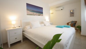 A bedroom with a bed, nightstands, a lamp, a chair, and a wall-mounted air conditioner. - 250 - Casa Birgit (Tarifa)